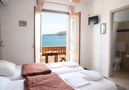 two beds in a room with a view of the ocean at Three Brothers in Mandrákion