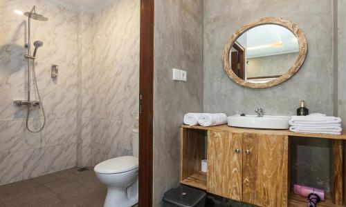 a bathroom with a sink and a toilet and a mirror at Rumah Weda in Ubud