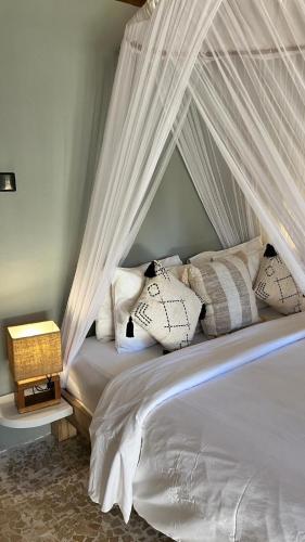 a bedroom with a canopy bed with pillows at Café Gili Beach Bungalows in Gili Meno