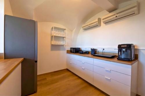 a kitchen with white cabinets and a coffee maker on the counter at Old Town Guest Accommodation in Kranj