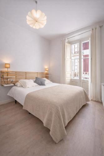 a white bedroom with a large bed and a chandelier at 22CaLQuEROL Boutique centro suite lux in Puigcerdà