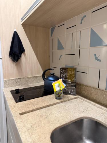 a kitchen counter with a sink and a kettle on a stove at 710 A Hotel Home Jade in Brasília