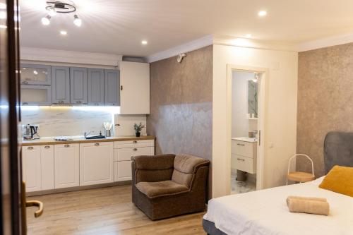 a bedroom with a bed and a chair and a kitchen at Studio Glen in Târgu-Mureş