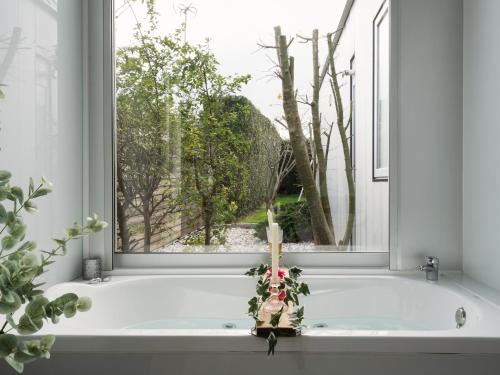 a bath tub with a window with a candle in it at Casa Calima in Esteiro