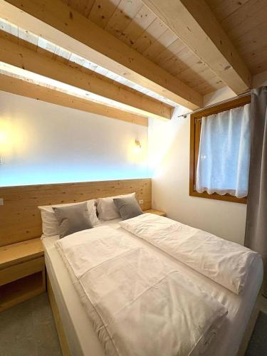 a bedroom with a large white bed with a window at Casa ecologica Ai Ronchi in Gallio