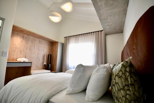 a bedroom with a bed with white pillows and a window at Rustic Hills 39 in Swakopmund