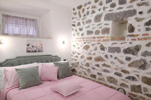 a bedroom with a pink bed with a stone wall at La casa di Armida in Radicofani