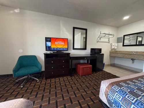 a hotel room with a bed and a desk and a television at Budget Inn Ada in Ada