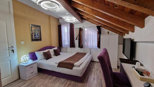a bedroom with a bed and a desk and a tv at Pansion Oscar Summer Garden in Mostar
