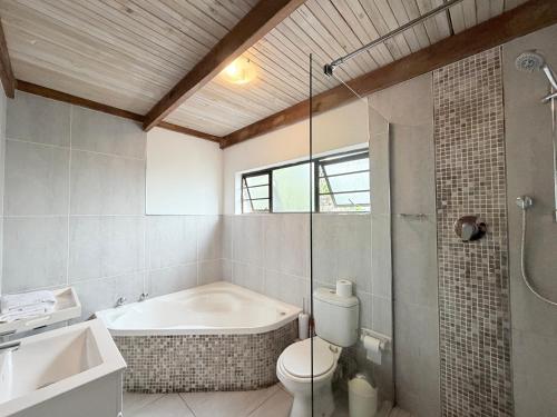 a bathroom with a tub and a toilet and a shower at The Hide on 37 Flamingo in East London