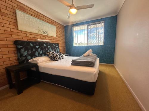 a bedroom with a bed in a brick wall at Beachlander Self-Contained Holiday Apartments in Coffs Harbour