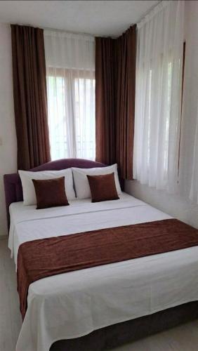 a bedroom with a large white bed with windows at Pansion Oscar Summer Garden in Mostar