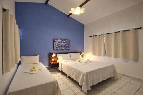 a bedroom with two beds and a blue wall at Pousada Arriba Pipa in Pipa