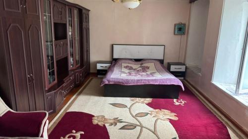 a bedroom with a bed and a red rug at Sheki Ev Guest House in Sheki
