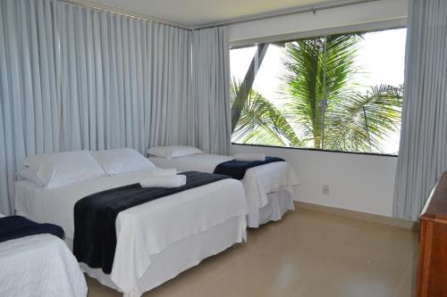 a hotel room with two beds and a palm tree at Pousada Suítes do Lago in Capitólio