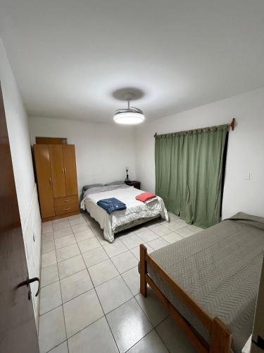 a bedroom with two beds and a green curtain at Casa Mitre in Luján
