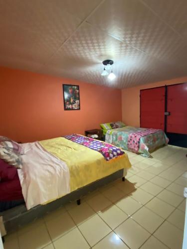 a bedroom with two beds and orange walls at Abril hospedaje in Juayúa