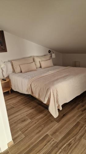 a bedroom with a large white bed with a wooden floor at La Posada del Olivar in Baena