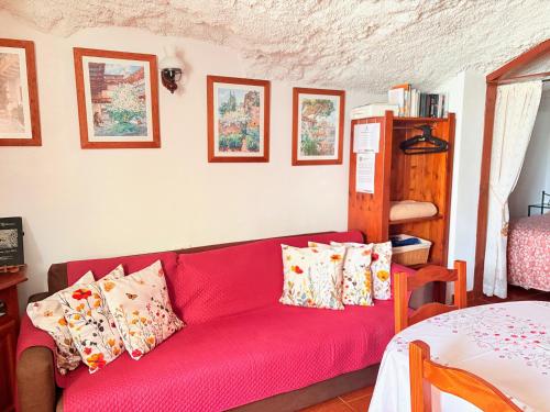 a red couch in a living room with pillows at Finca Las Polinarias Casa Cueva en Fasnia in Santa Cruz de Tenerife