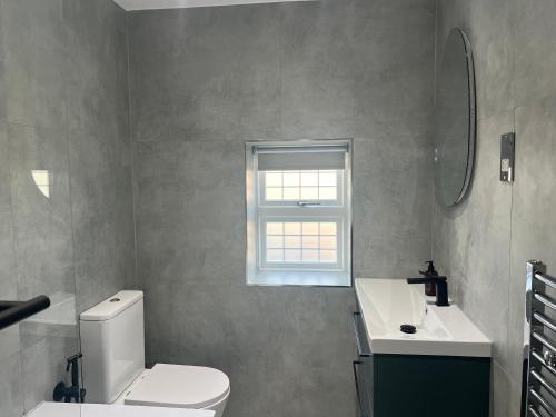 a bathroom with a toilet and a sink and a window at Luxury 4BR Bungalow in Hackbridge