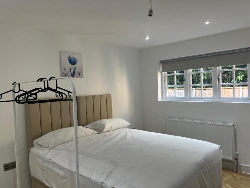a bedroom with a bed with white sheets and a window at Luxury 4BR Bungalow in Hackbridge