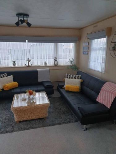 a living room with a black couch and a table at Holiday Sea Caravan in Withernsea