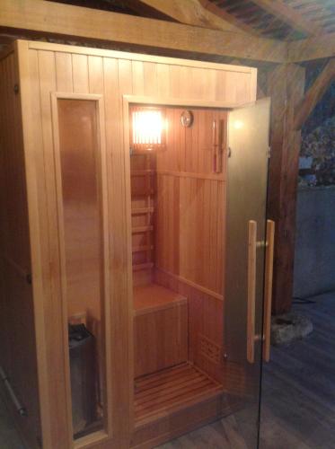 einen Holzschrank mit einem Kühlschrank in einem Zimmer in der Unterkunft Le Colombier de la Graverie in Senots