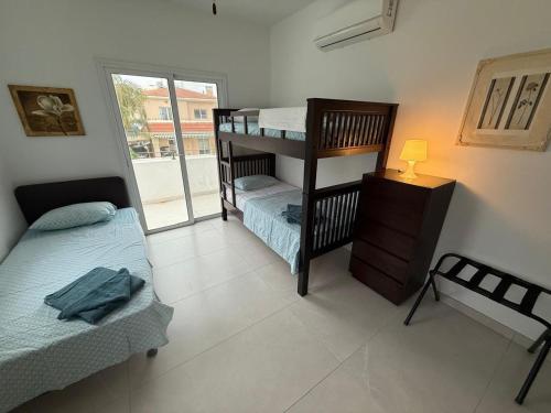 a bedroom with two bunk beds and a window at Villa Artemis - 150m from Kapparis Beach in Paralimni
