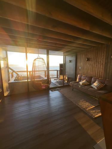 a living room with a couch and a swing at Rukamar Cocholgue in Tomé