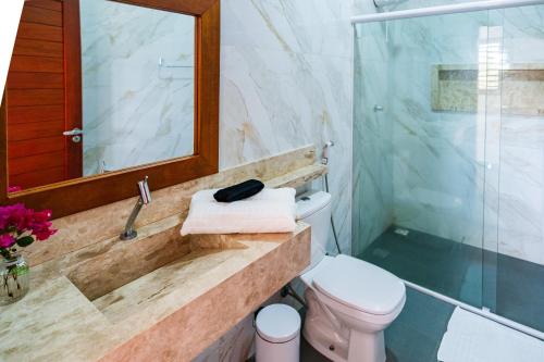 a bathroom with a sink and a toilet and a mirror at Pousada Brisa do Cardeiro in São Miguel do Gostoso