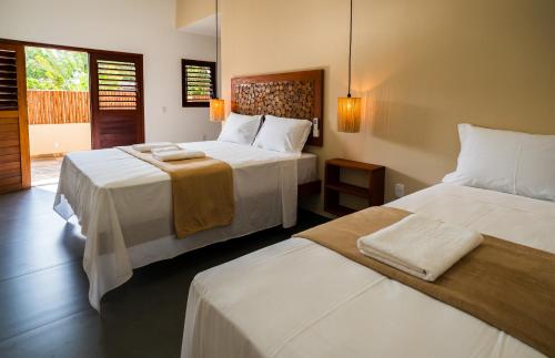 a bedroom with two beds with white sheets at Pousada Brisa do Cardeiro in São Miguel do Gostoso