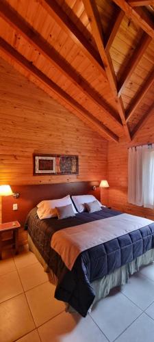 a bedroom with a large bed in a wooden room at Encanto del Rio in Villa La Angostura