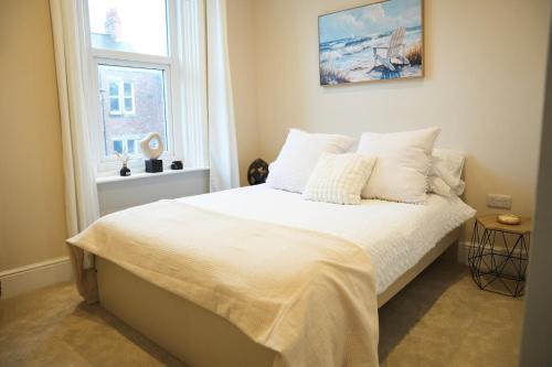 a bedroom with a bed with white sheets and a window at Modern 2 Bed 2 Bath Apartment in Prime Jesmond Location in Newcastle upon Tyne