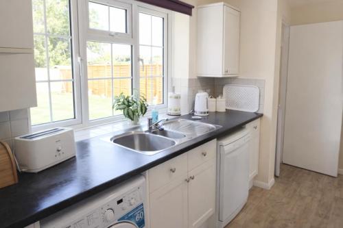 a white kitchen with a sink and a window at Oxford Cottage in Wheatley - Parking & Garden in Wheatley