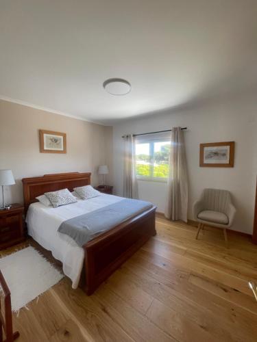 a bedroom with a bed and a window and a chair at Lagoa House Albufeira in Lagoa de Albufeira