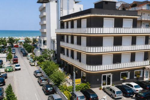 a building with cars parked in a parking lot at Hotel Rivamare Room only and free coffee room in Cervia