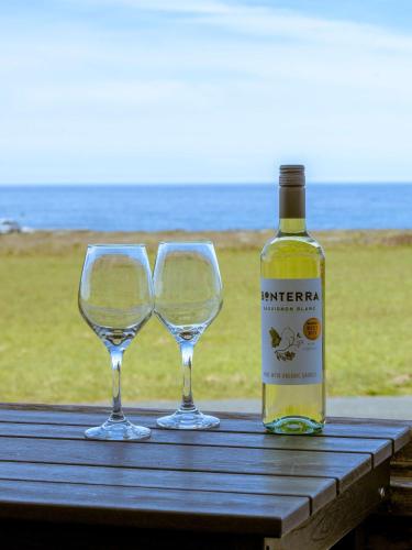 a bottle of wine and two wine glasses on a table at Dog Friendly Oceanfront Home with Hot Tub & Views in Fort Bragg