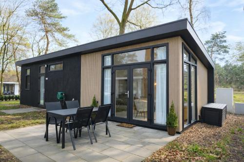 a black tiny house with a table and chairs at Colibri Huisje in Haarle