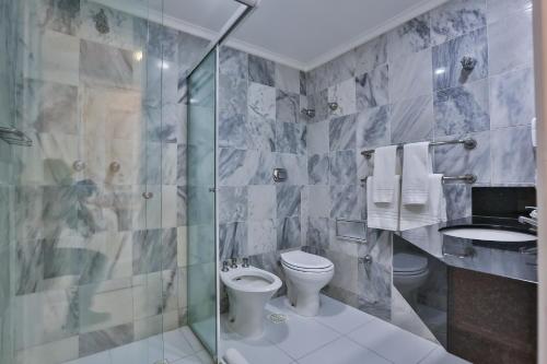 a bathroom with a shower and a toilet and a sink at Itapema Beach Hotel & Convention in Itapema