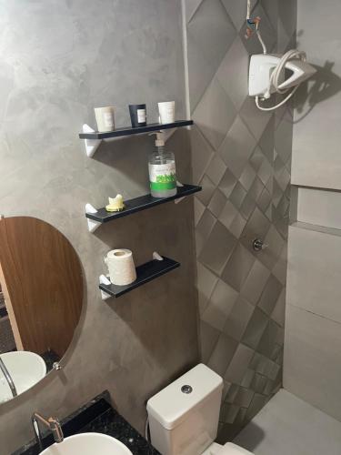 a bathroom with a toilet and shelves on the wall at Casa Lima Premium in Arapiraca