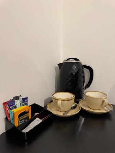 two cups on a table with a tea pot at Beautiful Private Ensuite Minutes to city centre in Stoke on Trent