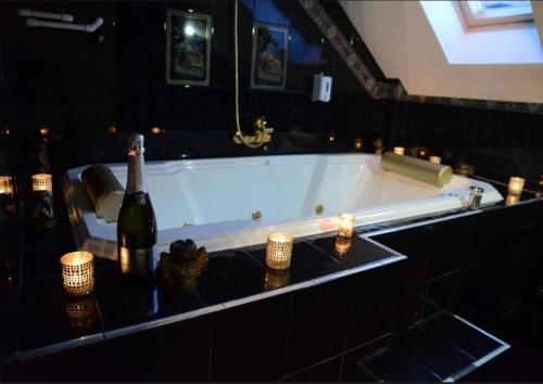 a bath tub with a bottle of wine and candles at Guest House Vivaldi in Niš