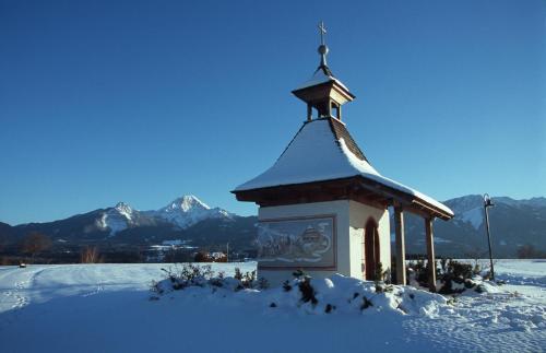 a small chapel in the snow with mountains in the background at Gästehaus Lutschounig in Faak am See