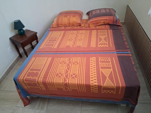 a bed with an orange and orange comforter and a table at Villa Greg in Bouillante