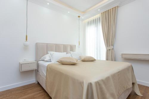 a white bedroom with a bed with two pillows on it at Apartment Harmonia in Dobrota