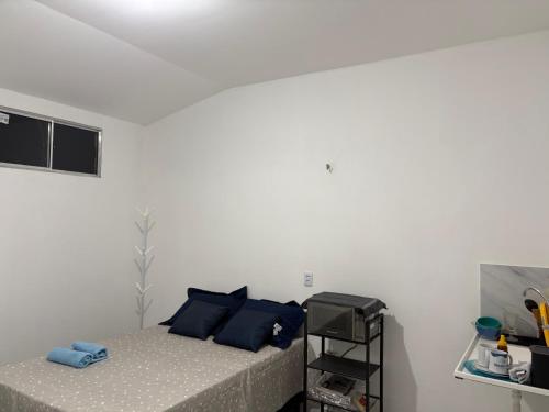 a white bedroom with a bed with blue pillows at Studio suite casal in Teresina