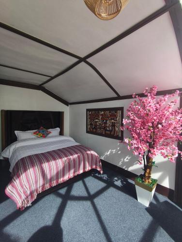 a bedroom with a bed and a tree with pink flowers at LAKE TITICACA LODGE in Puno