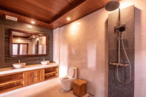 a bathroom with a toilet and a sink and a shower at Taru Sebatu Villa in Ubud