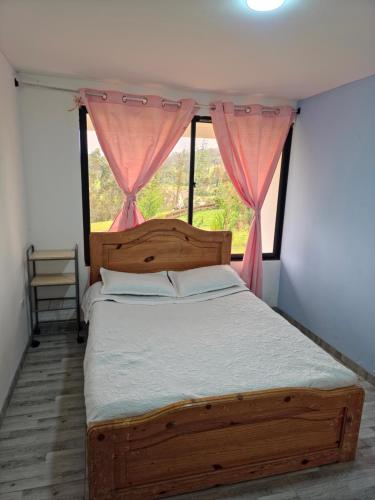 a bedroom with a wooden bed with a window at "Refugio campestre familiar - Cálido, cómodo y totalmente equipado" y zona de juegos in Nariño