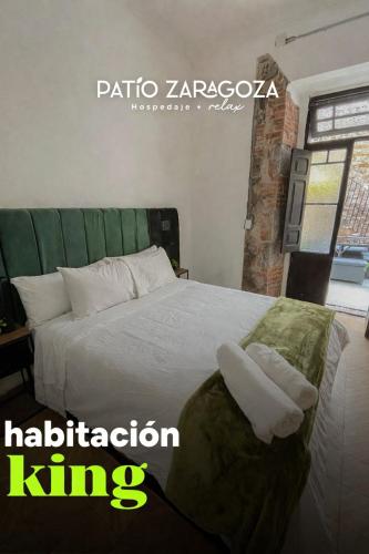 a bedroom with a white bed with a green headboard at Hotel PATIO ZARAGOZA, Centro Histórico SLP in San Luis Potosí